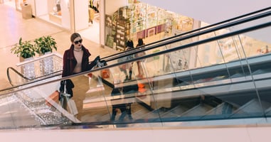 Model on an escalator with her shopping bags